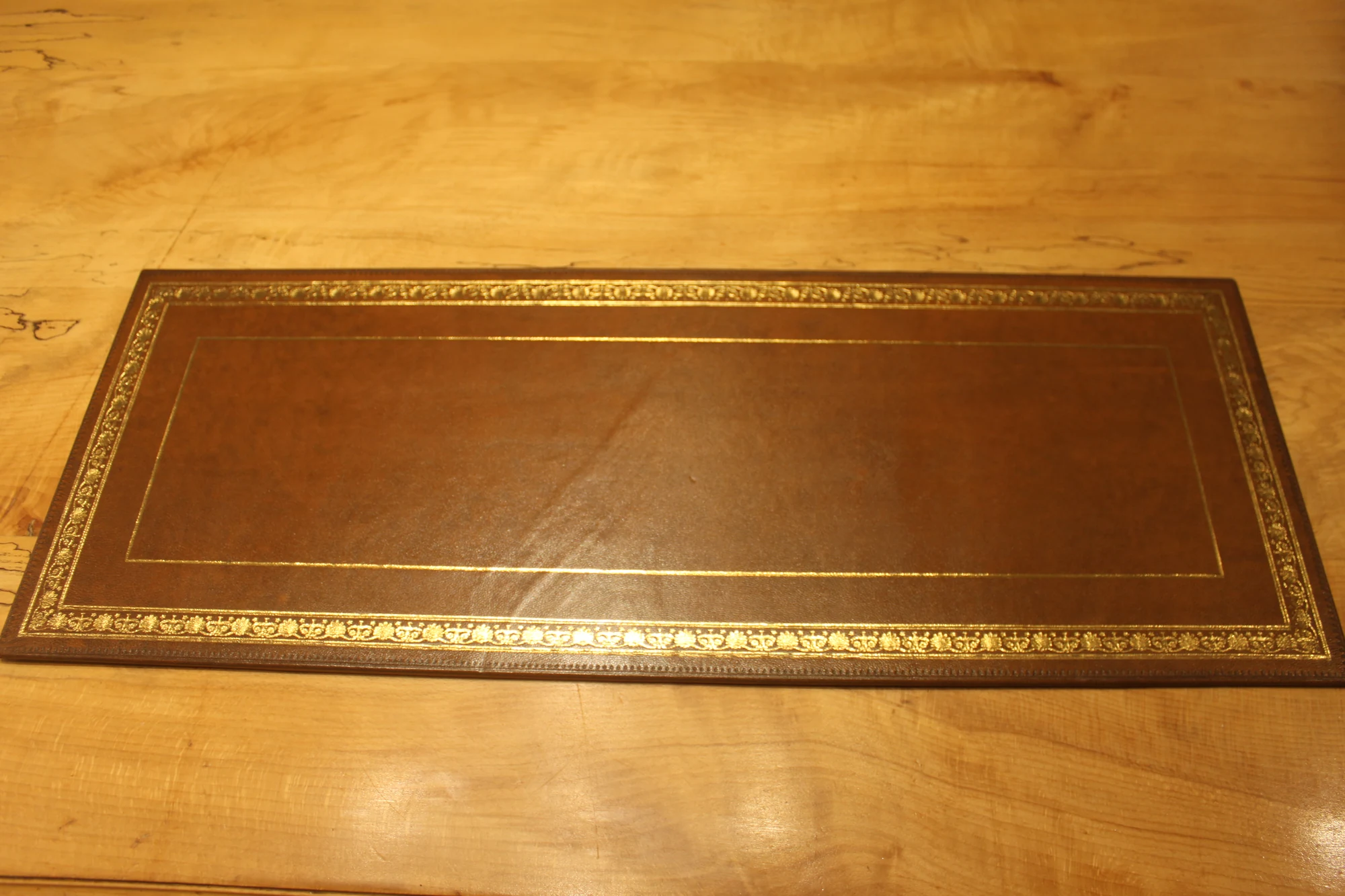 Wide desk pad 12 with a floral border, photographed on a wooden worktable